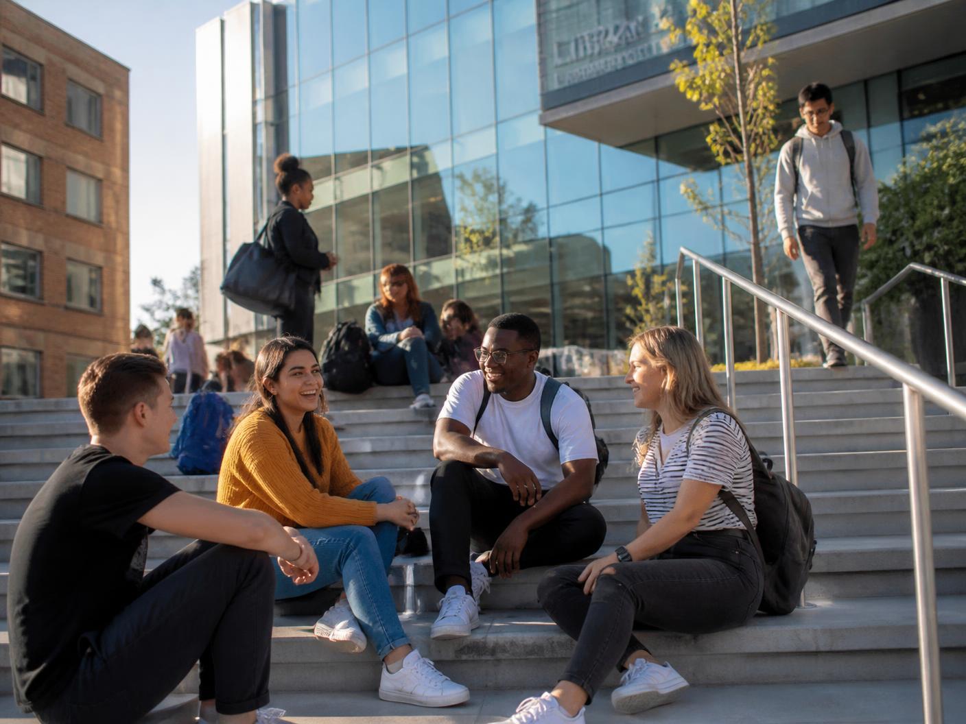 Students on the steps of a modern UK university library